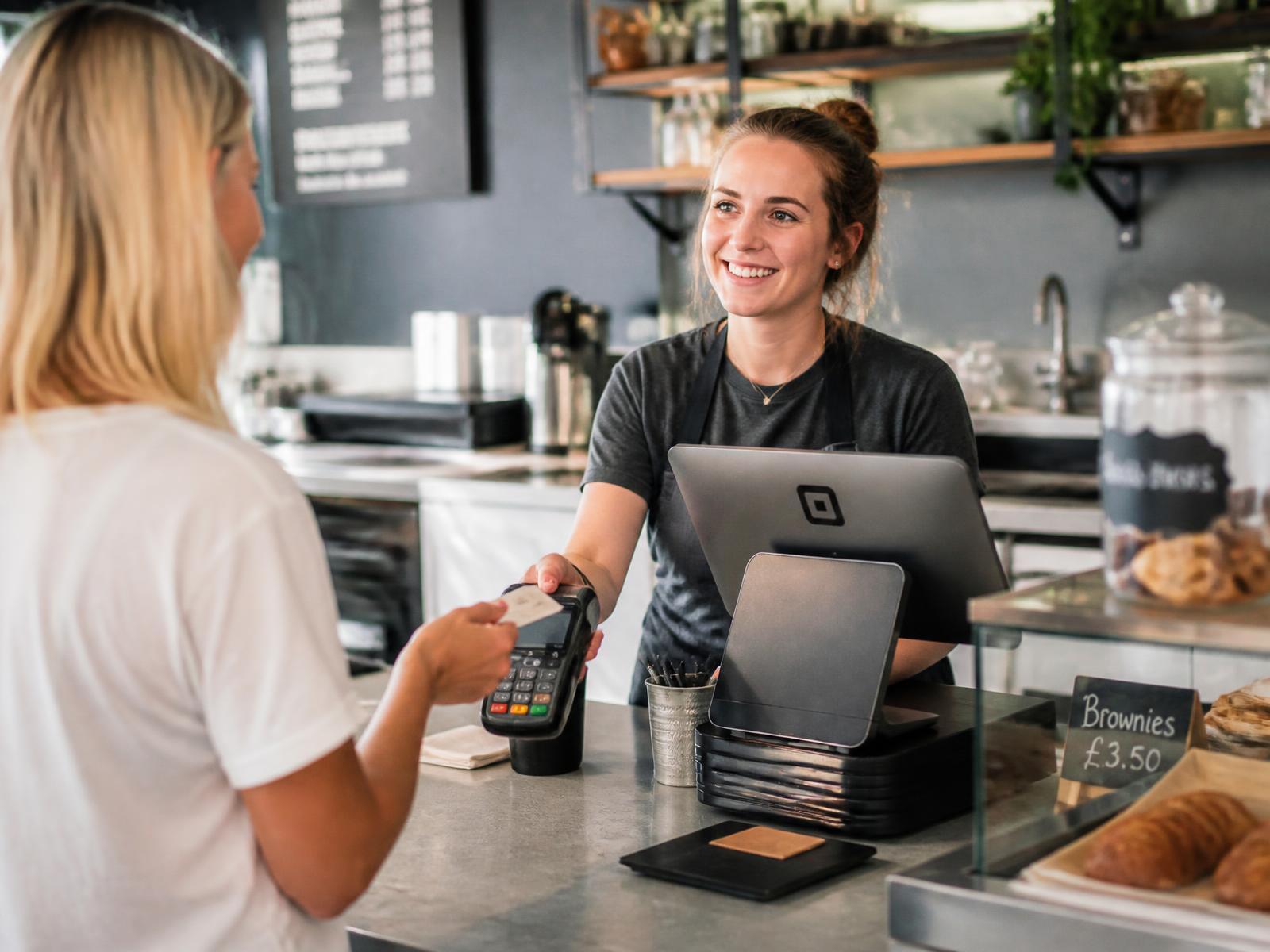 Customer paying by contactless card at a café counter with a modern till system